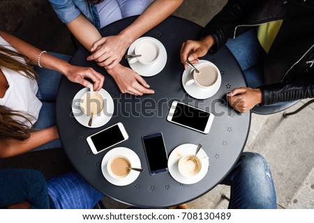 Top view of hands with coffee cups and smartphones on table in a urban cafe.