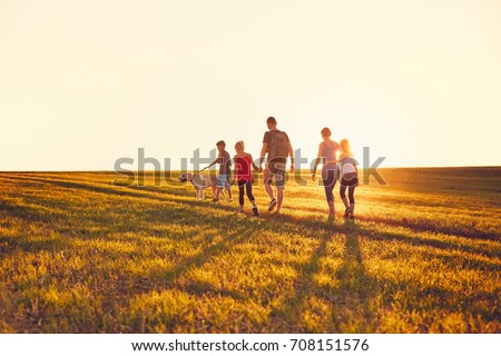 Summertime in the countryside. Silhouettes of the family with dog on the trip at the sunset.