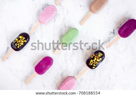 Flat lay with colorful popsicles on white marble table. Summer ice cream pattern
