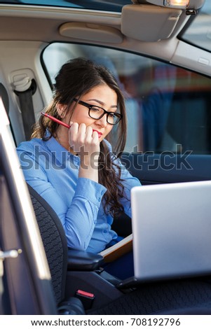 Beautiful young business woman sitting in the car with laptop.