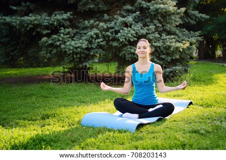 Girl is engaged in yoga in the park, doing exercises. Concept sport healthy lifestyle.