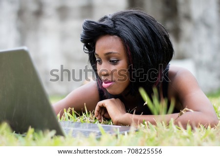 pretty woman lying on herbs, is focused on her laptop in front of her.
