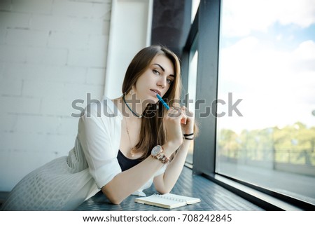 Portrait of trendy young caucasian woman posing near a window. Young brunette women working in office. 