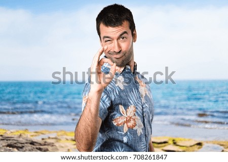 Handsome man with flower shirt making OK sign at the beach