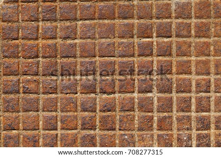 Old rusty sewer metal hatch, photographed close-up. The hatch has an uneven structure and is divided into squares
