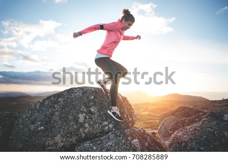 Athletic woman running in the mountains at sunset against the backdrop of a beautiful landscape. Sport tight clothes. Intentional motion blur. Royalty-Free Stock Photo #708285889