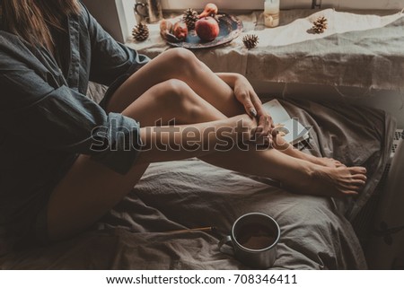 Cozy home. Woman with cup of hot drink sitting by the window. Selective focus.