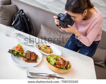 Women hold a camera in a hand and taking a picture for review in her blog.