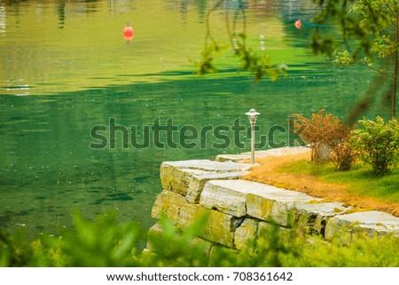Garden decoration near lake water, island made of decorative stone bricks and outdoor lamp