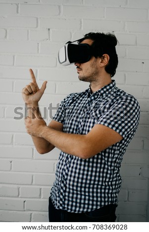 Man wearing virtual reality goggles with smartphone. Watching movies or playing video games - closeup. Male looking in VR glasses, isolated on white brick background. chines virtual reality