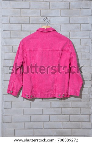 picture of a part of pink Female jacket  on white brick wall
