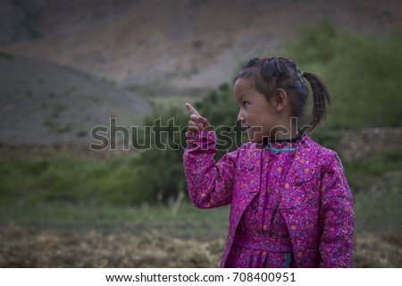rural indian girl pointing somewhere in traditional dress near kaza, himachal pradesh, india