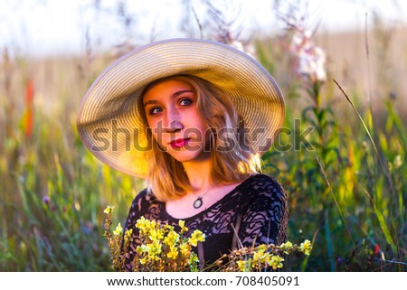 portrait of a young beautiful teenage girl in a field with a hat and bouquet of wildflowers
