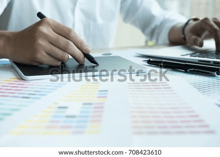 male graphic designer working with computer and color swatch. creative man using stylus pen and digital tablet at modern office. Architect using work tools and sample colour catalog. business, 