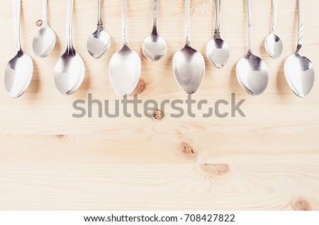 Collection rustic empty spoons on beige wood background. Mock up for designer, restaurant menu, advertising.