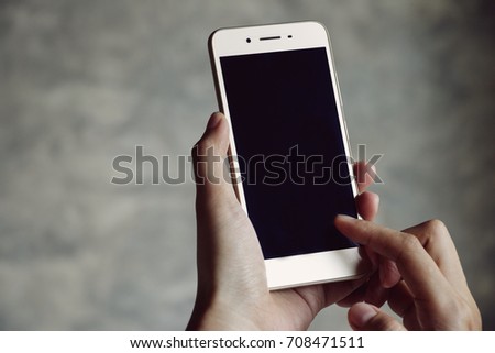 A woman holding device and touching screen. Hands holding phone selective focus.