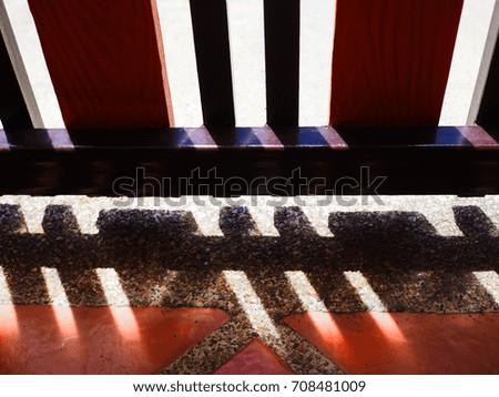 Dark red and black wooden iron fence gate, with sunlight shade and shadow grille stripe reflection on grainy texture stone orange clay tile floor, horizontal arranged
