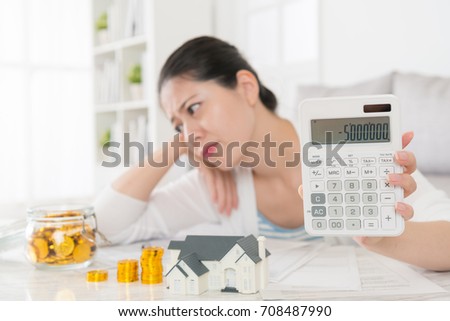 selective focus photo of beautiful young mother showing negative number on calculator and looking at deposit coins feeling confused.