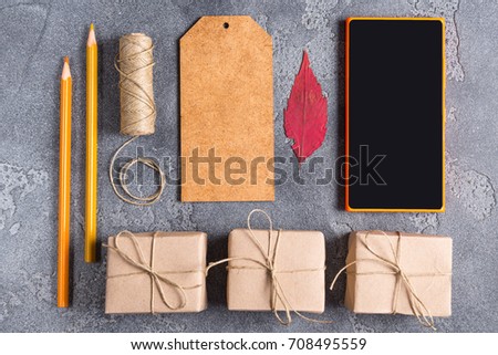 Craft tools, smart phone and gift boxes on grey background