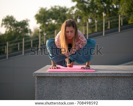 Young beautiful caucasian woman doing yoga asana in the city. Summer morning.