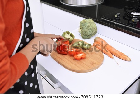Woman slicing peppers and cooking in the kitchen