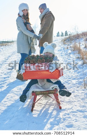 Family delivering christmas gifts in winter with sled 