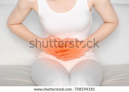 woman with Belly pain .Acute pain in a woman stomach. Female holding hand to spot of stomachache. Concept photo with read spot indicating location of the pain.