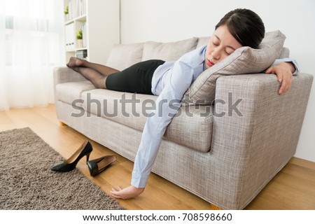 young pretty business woman after work lying down on sofa couch sleeping resting when she working long time and feeling tired. Royalty-Free Stock Photo #708598660