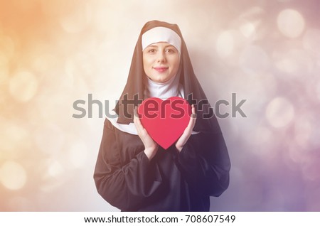 Young smiling nun with heart shape box on white background