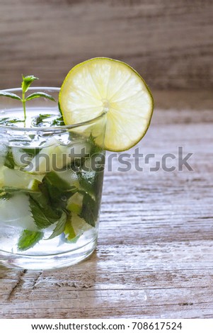 Mojito cocktail with lime and mint in highball glass on a white wooden background, toned