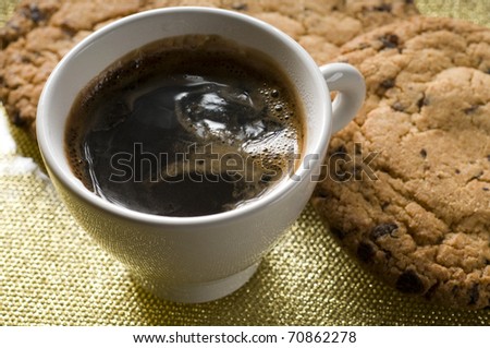 Coffee cup and chocolate cookies on a plate over color background