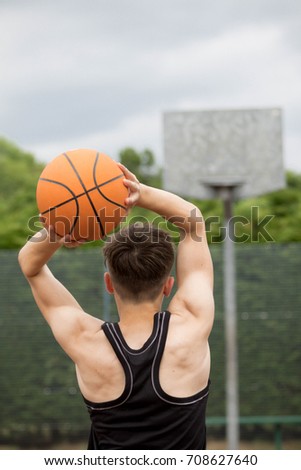 Teenage boy shooting a hoop on a basketball court
