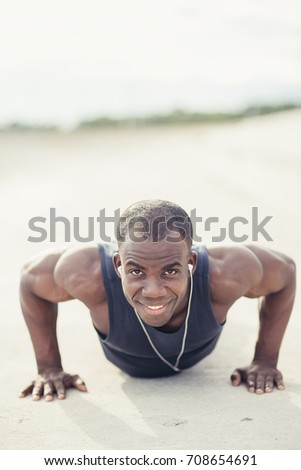 Portrait of a young black man doing push ups at the beach