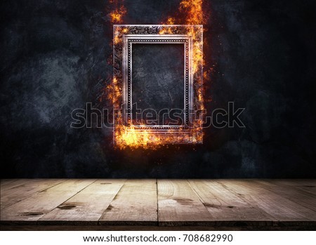 Fire Burning silver Antique picture Frame on dark grunge wall with Wooden table top, Empty ready for product display or montage.