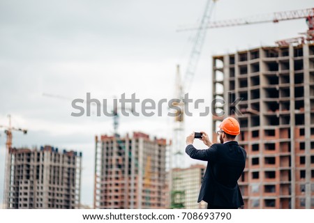 Construction engineer with the smartphone. Pictures of the construction site