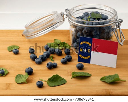 North Carolina flag on a wooden plank with blueberries isolated on white