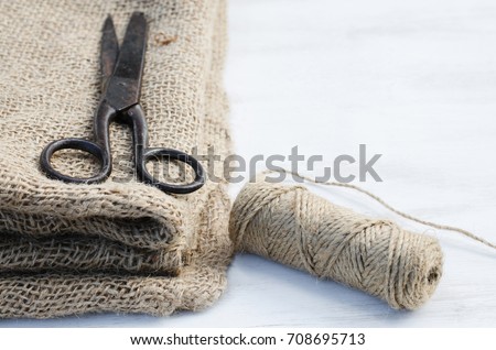 Old scissors, skein jute twine and burlap on a wooden background. Rustic style. Selective focus.