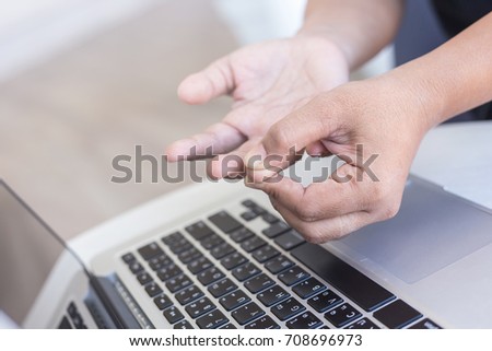 Close up woman holding and pressing or touching her finger while working with laptop in the office. Numbness or pain on finger  concept.