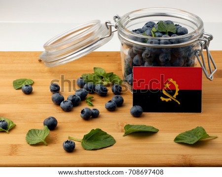 Angolan flag on a wooden plank with blueberries isolated on white