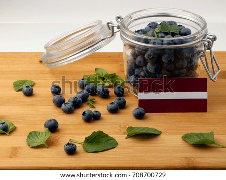 Latvia flag on a wooden plank with blueberries isolated on white