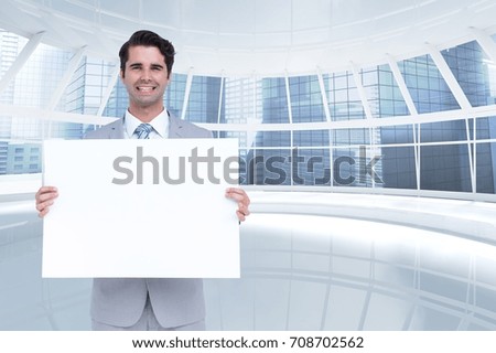 Digital composite of Happy business man holding blank card in office