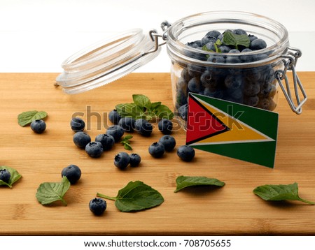 Guyana flag on a wooden plank with blueberries isolated on white