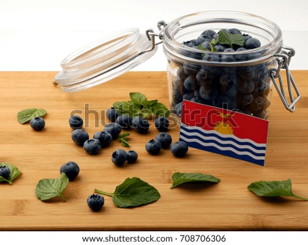 Kiribati flag on a wooden plank with blueberries isolated on white