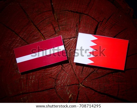 Latvia flag with Bahraini flag on a tree stump isolated