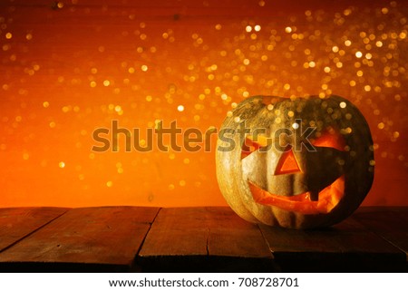 Halloween Pumpkin on wooden table in front of spooky dark background. Jack o lantern.