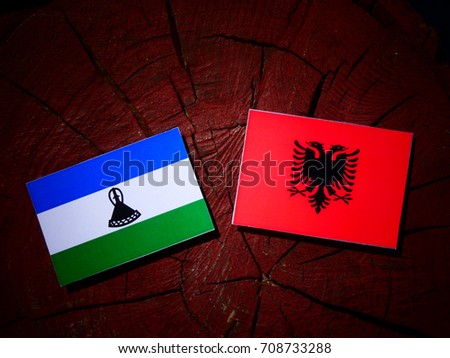 Lesotho flag with Albanian flag on a tree stump isolated