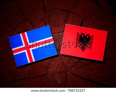 Icelandic flag with Albanian flag on a tree stump isolated