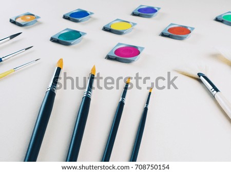 Watercolor and brushes at beige background. Flat lay, top view. Art and education concept.