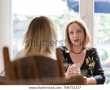 Young adult woman listen to opponent at informal business meeting. Horizontal low angle perspective, candid shot. Royalty-Free Stock Photo #708752227