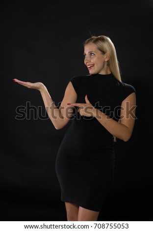 Young enlivened woman portrait of a confident businesswoman showing by hands on a black background. Ideal for banners, registration forms, presentation, landings, presenting concept